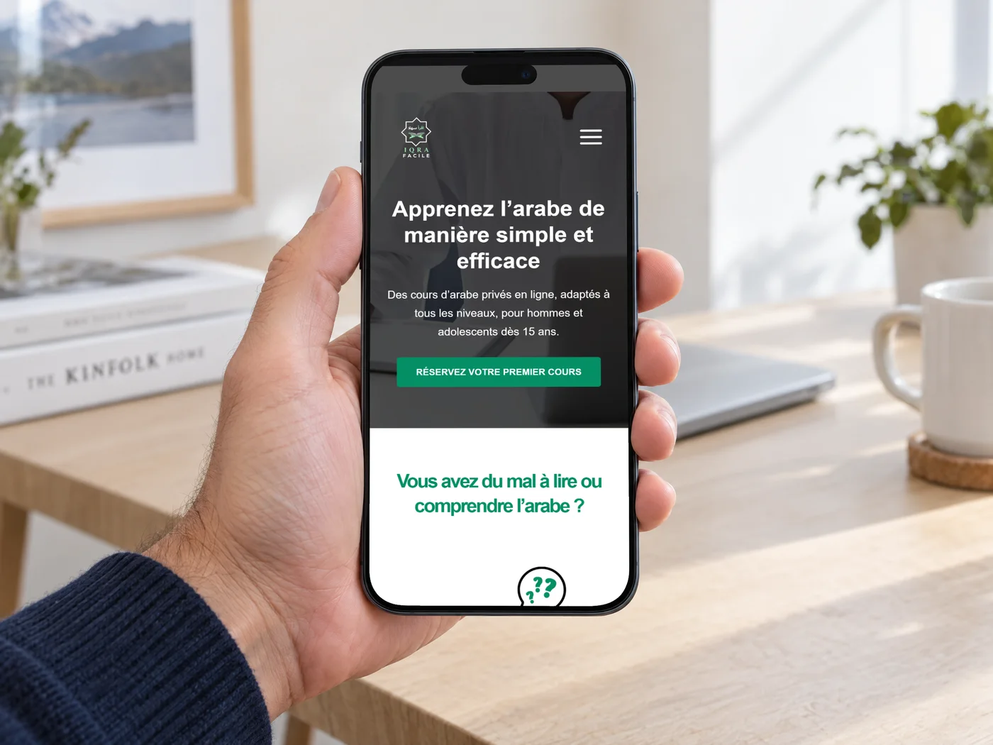 Un iPhone tenu en main affichant l'accueil d'IQRA Facile