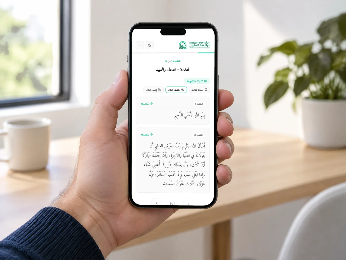 Un iPhone tenu en main affichant une fiche de Mutun Talib 3ilm, paragraphes révélés en arabe vocalisé